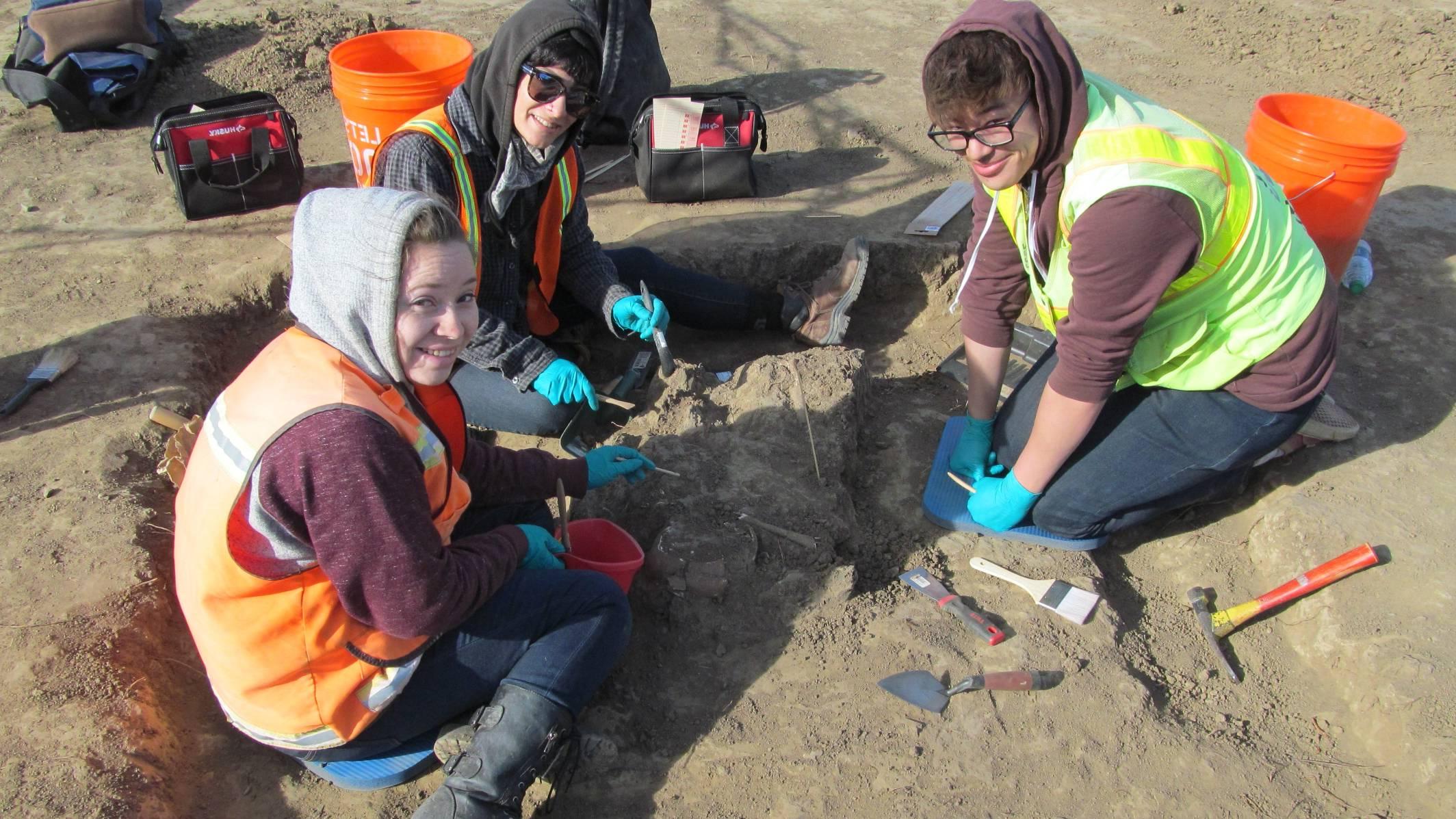 Three anthropolgy students working on a dig